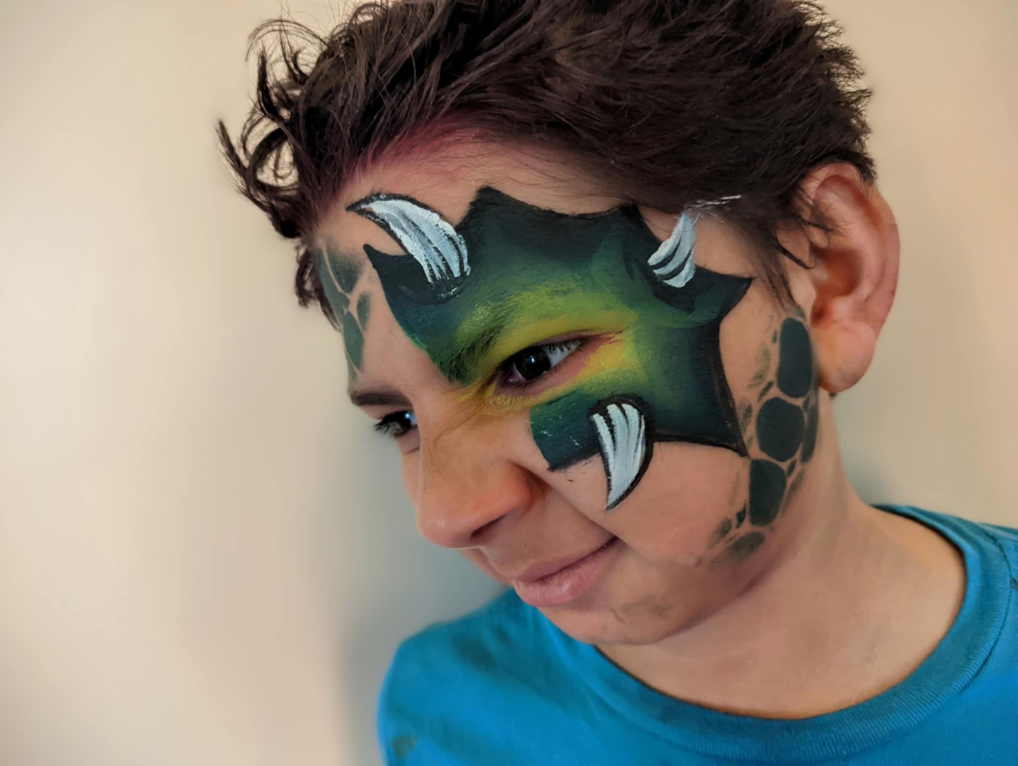 Child with a dragon eye mask face painting design