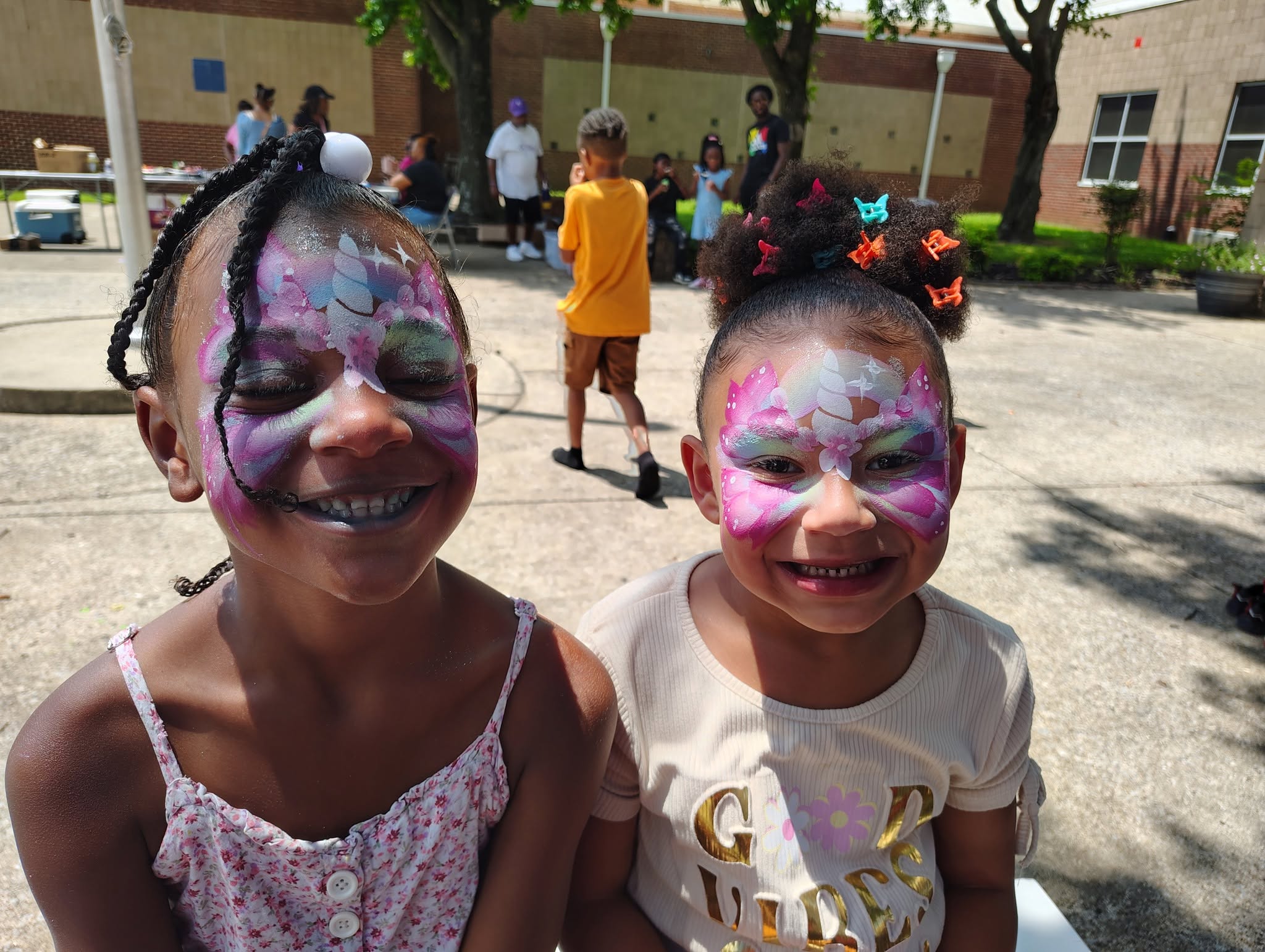 Two girls with unicorn and butterfly face painting designs